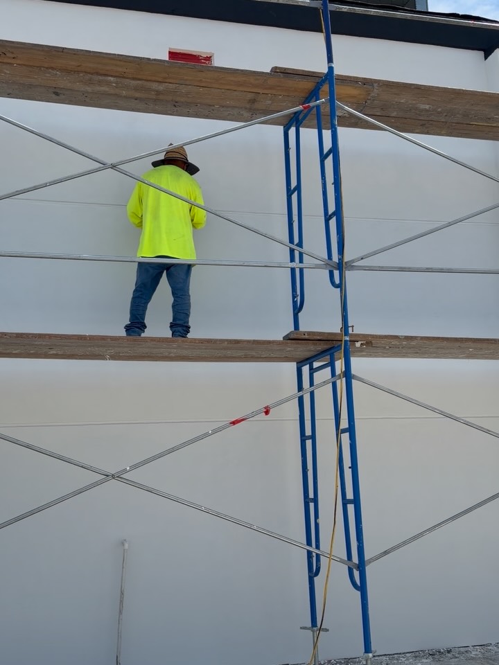 Stucco craftsman on scaffolding finishing a white wall